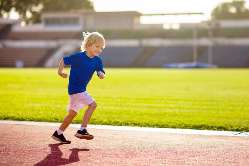 Child running in stadium. Kids run. Healthy sport.