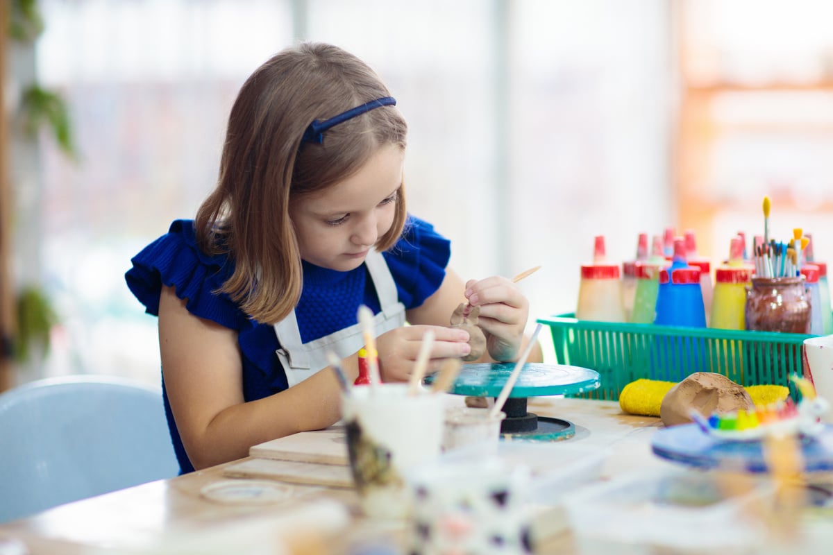 Child at pottery wheel. Kids arts and crafts class